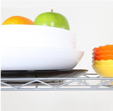 White bowl with green apple and orange on a metal shelf with additional colorful bowls.